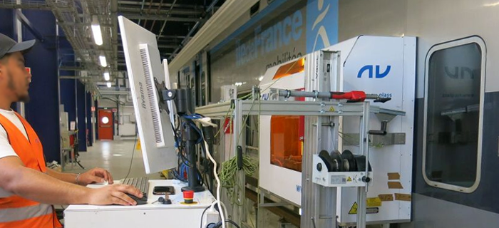 Un agent en atelier de maintenance entrain d'effectuer une opération sur les vitres d'un train Regio 2N.